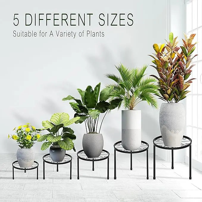 Set of planters with plants on small round stands against a white wall.