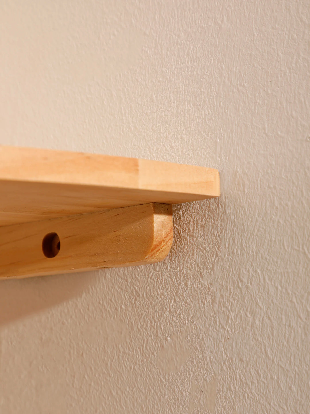 Wooden shelf attached to a beige wall