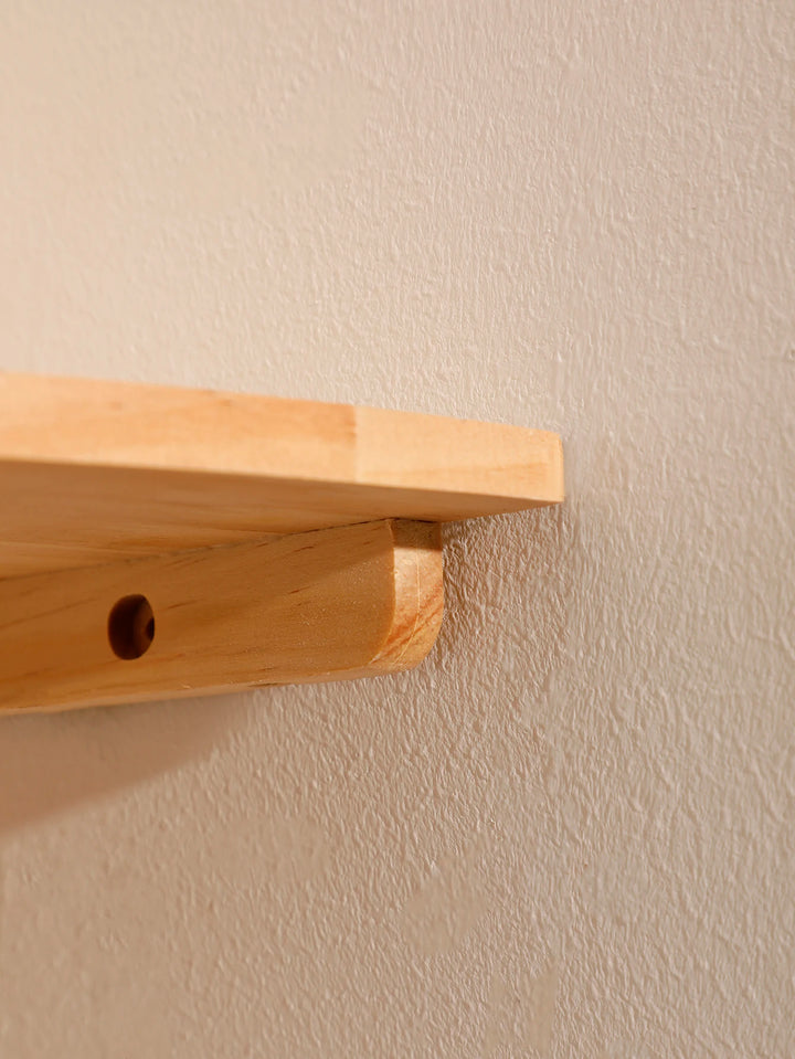 Wooden shelf attached to a beige wall