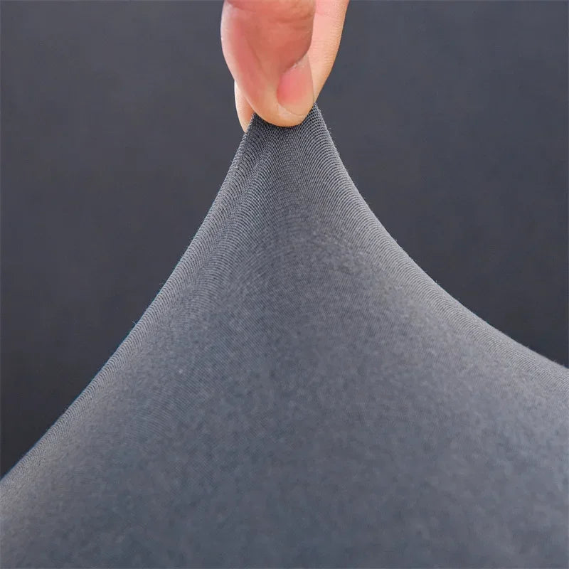 Close-up of gray fabric being held with a finger against a dark background