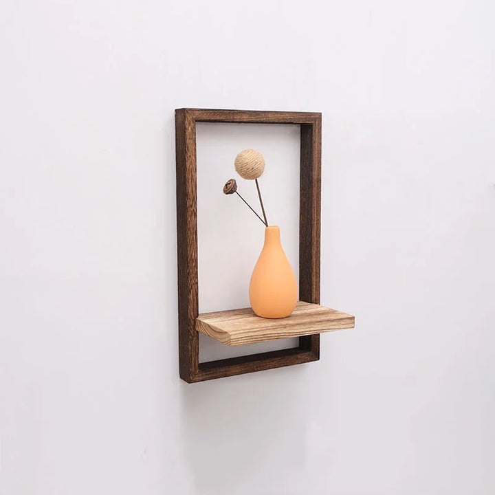 Wooden shelf with an orange vase and dried flower on a white wall